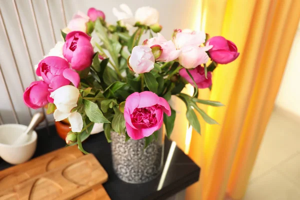 Florero con ramo de hermosas peonías en la mesa en la cocina — Foto de Stock