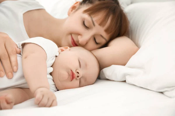 Wanita muda dengan bayi tidur yang lucu berbaring di tempat tidur di rumah — Stok Foto