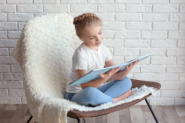 Petite fille assise sur une chaise avec un livre — Photo