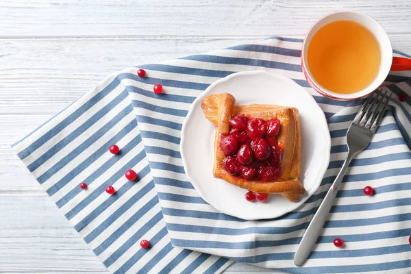 Plate with puff and cherry on striped napkin — Stock Photo, Image