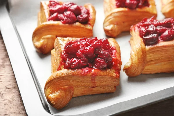 Plateau avec de délicieuses pâtisseries feuilletées et cerise sur table en bois — Photo