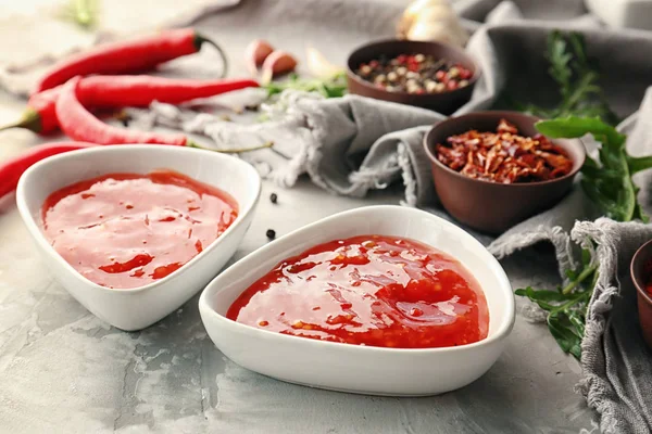 Molho de pimenta saborosa em tigelas e ingredientes na mesa — Fotografia de Stock