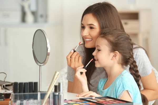 Mujer e hija pequeña aplicando maquillaje —  Fotos de Stock
