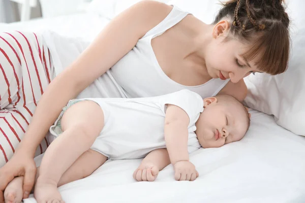 Wanita muda dengan bayi tidur yang lucu berbaring di tempat tidur di rumah — Stok Foto