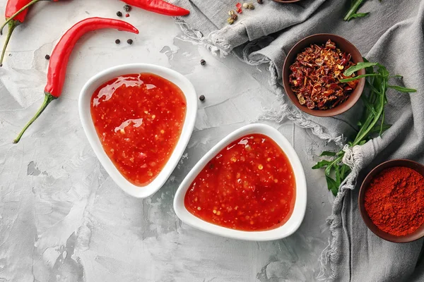 Molho de pimenta saborosa em tigelas e ingredientes na mesa — Fotografia de Stock