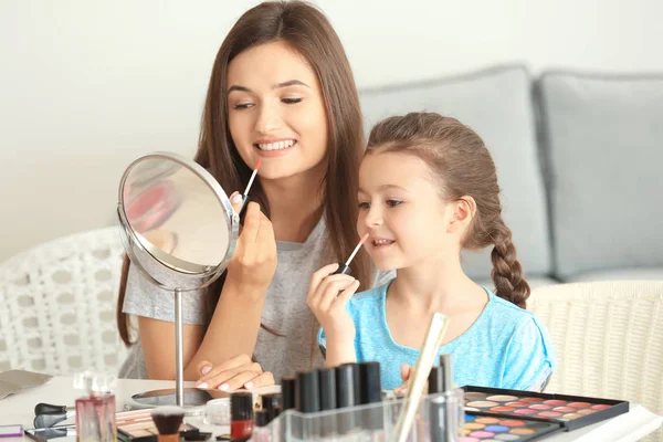 Mujer e hija pequeña aplicando maquillaje — Foto de Stock