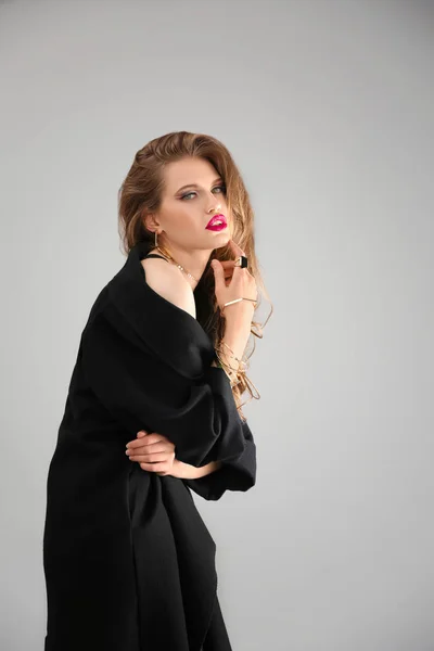 Красивая стильная женщина в темном пальто на сером фоне — стоковое фото