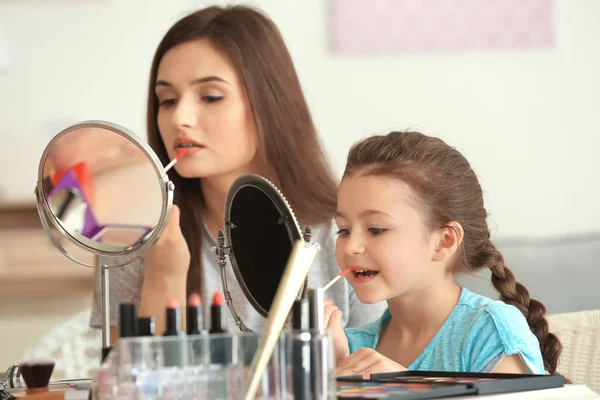 Mujer e hija pequeña aplicando maquillaje — Foto de Stock