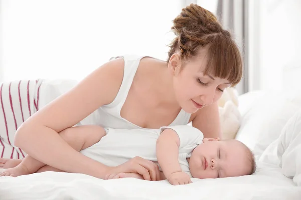 집에서 침대에 누워 귀여운 잠자는 아기와 젊은 여자 — 스톡 사진