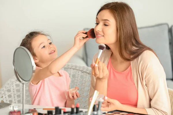 Mujer e hija pequeña aplicando maquillaje —  Fotos de Stock