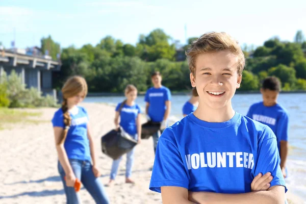 Young boy standing with crossed hands outdoors. Volunteer concept — Stock Photo, Image