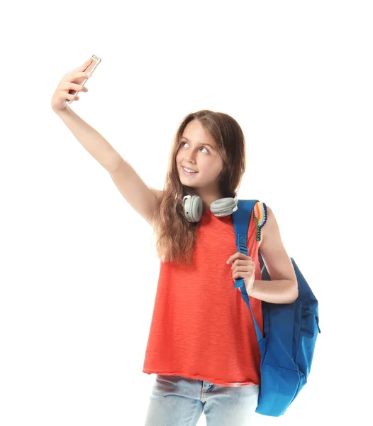 Cute teenager girl with headphones and schoolbag taking selfie on white background — Stock Photo, Image