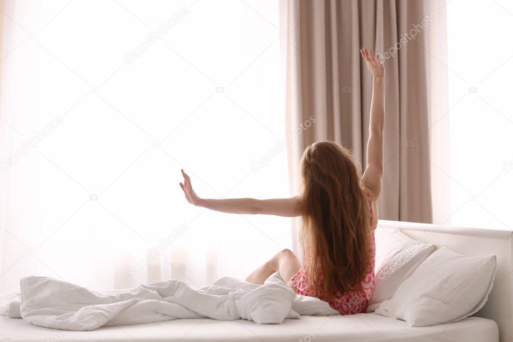 Morning of beautiful young woman sitting on bed at home
