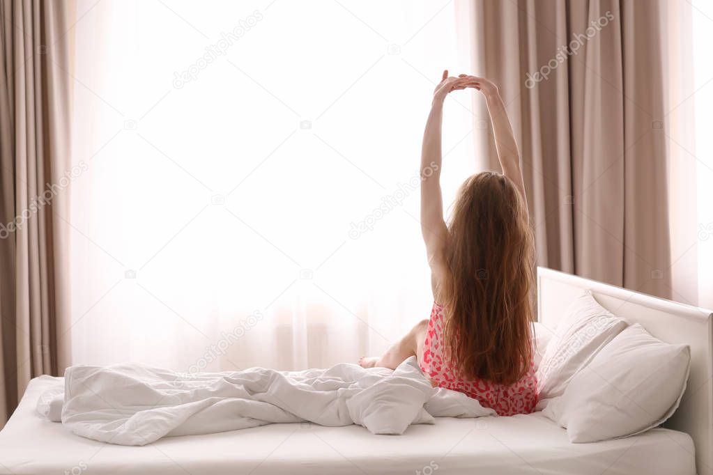 Morning of beautiful young woman sitting on bed at home