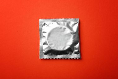 Kırmızı zemin üzerine sarılmış prezervatif