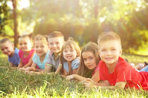 Bambini carini sdraiati sull'erba nel parco. Concetto vacanze scolastiche — Foto Stock