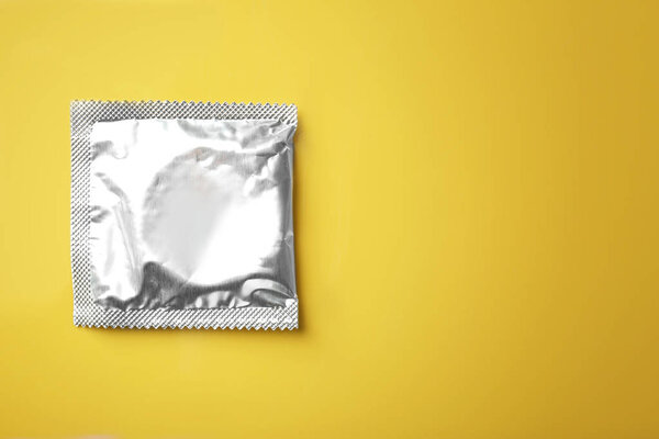 Завернутый презерватив на цветном фоне
