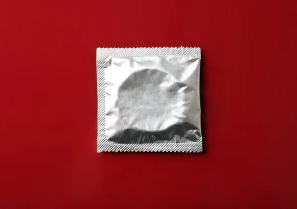 Загорнутий презерватив на бордовому фоні — стокове фото