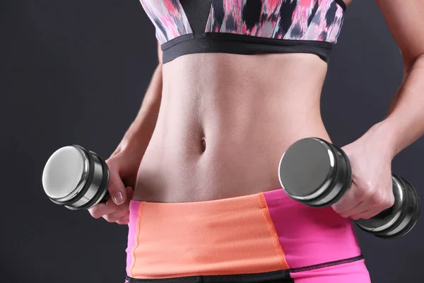 Woman in sport suit holding dumbbells — Stock Photo, Image