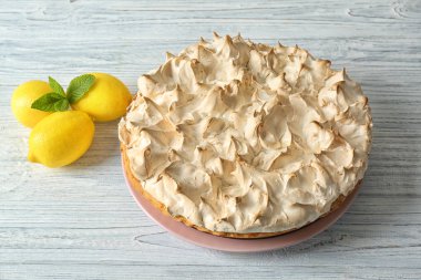 Plaka ile lezzetli limon beze pasta üzerinde ışık ahşap masa