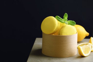 Lezzetli limon macarons koyu arka plan karşı masada ile kutu