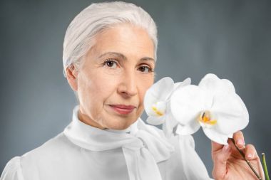 Güzel yaşlı kadın orkide çiçekleri ile 