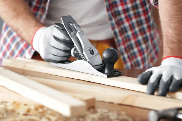 Timmerman schaven houten plank op tafel, close-up — Stockfoto