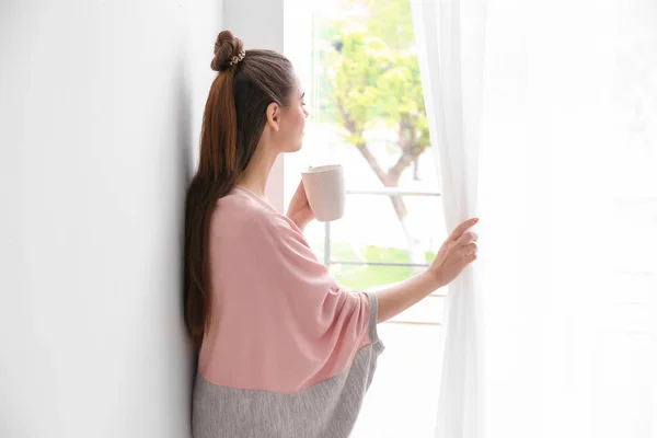 Belle femme buvant du café et regardant par la fenêtre — Photo