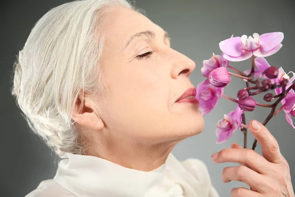Красива літня жінка з орхідеями — стокове фото