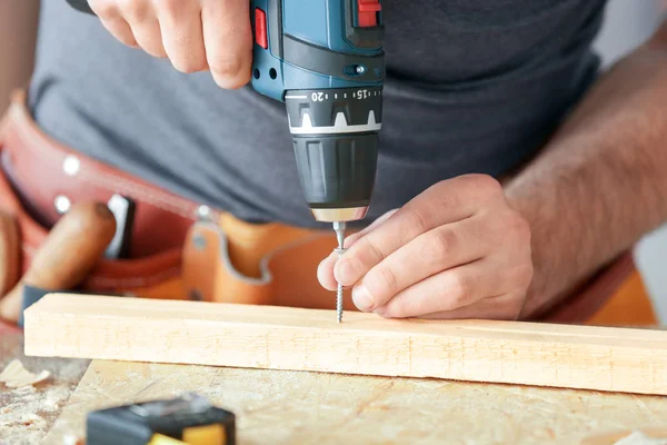 Carpenter driving screw nail into wooden plank in workshop — Stock Photo, Image