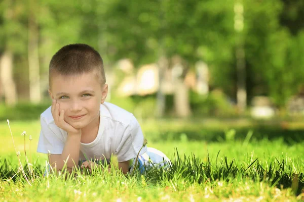 Carino bambino sdraiato su erba verde nel parco — Foto Stock