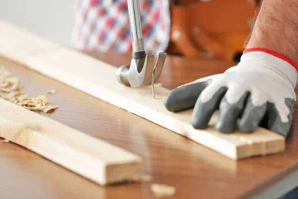 Carpenter pulling out nail from wooden plank, closeup — Stock Photo, Image