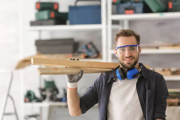 Smiling carpenter holding wooden planks