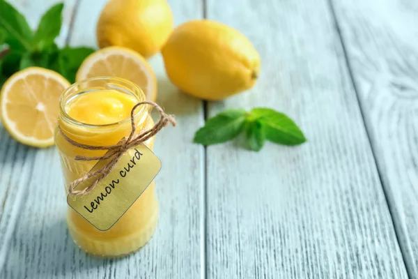 Glass jar with yummy lemon curd on wooden table — Stock Photo, Image