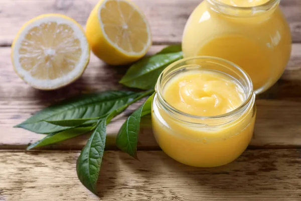 Pots en verre avec du citron caillé délicieux sur une table en bois — Photo