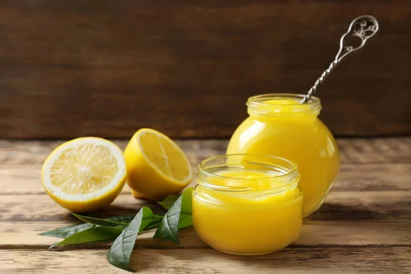 Glass jars with yummy lemon curd on wooden table — Stock Photo, Image