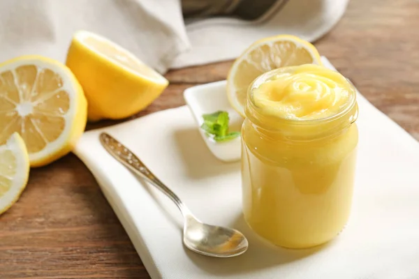 Glass jar with yummy lemon curd on wooden table — Stock Photo, Image