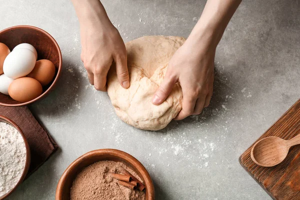 Woman kneading dough for cinnamon rolls on kitchen table — Stock Photo, Image