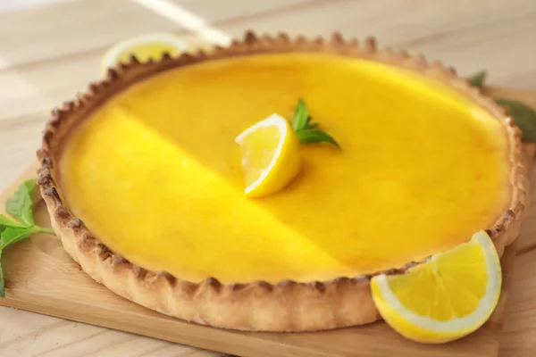 Houten plank met lekkere citroen wrongel taart op tafel, close-up — Stockfoto