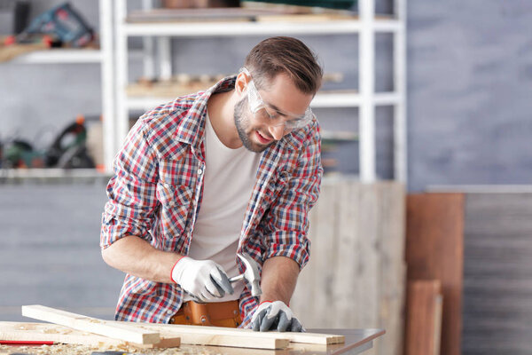 Carpenter driving nail into wooden plank