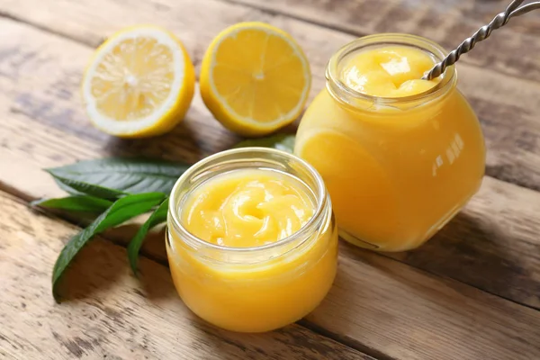 Pots en verre avec du citron caillé délicieux sur une table en bois — Photo