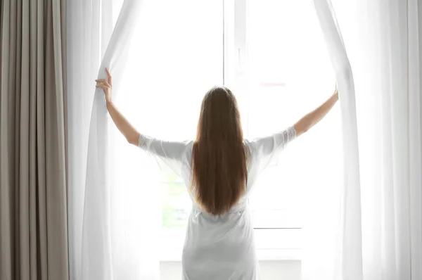 Woman looking out the window at home — Stock Photo, Image