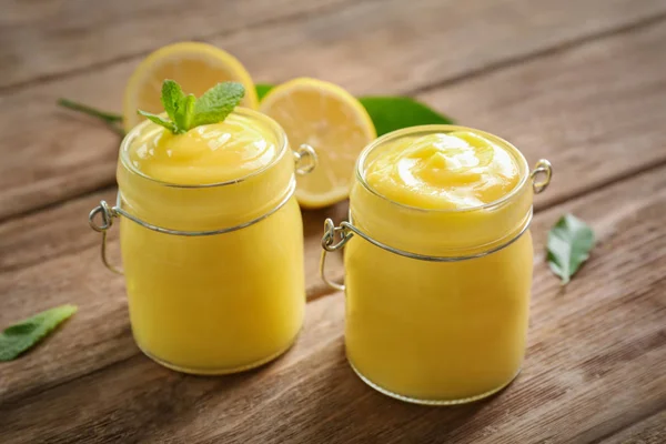 Glass jars with yummy lemon curd on wooden table — Stock Photo, Image