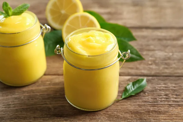 Pots en verre avec du citron caillé délicieux sur une table en bois — Photo