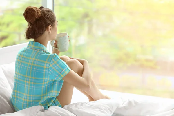 Женщина пьет кофе на кровати — стоковое фото