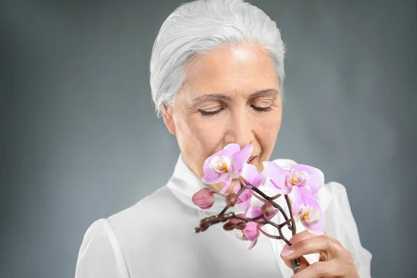 Schöne ältere Frau mit Orchideenblüten — Stockfoto