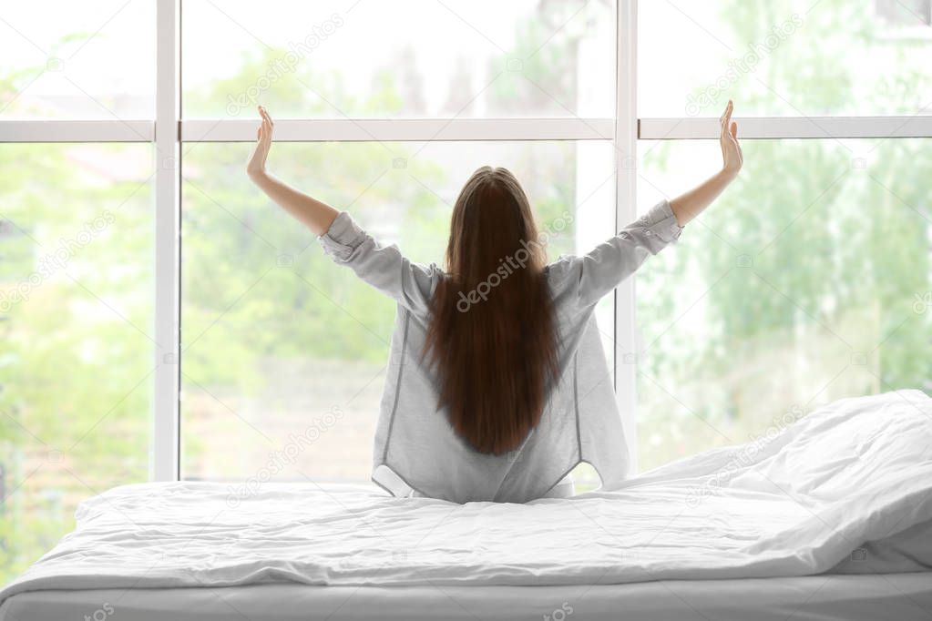 woman stretching after sleep against window