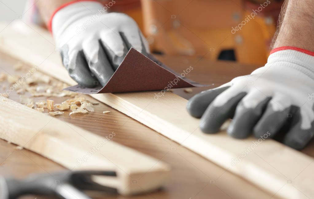 Carpenter sanding wooden plank 