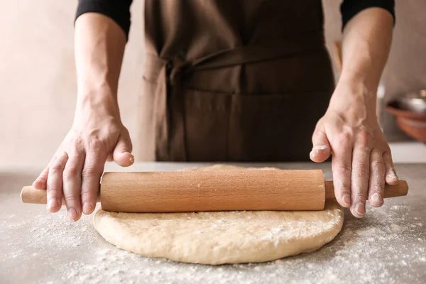 Женщина катит тесто для булочек с корицей на кухонном столе — стоковое фото