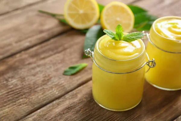 나무 테이블에 맛 있는 레몬 두 부와 유리 항아리 — 스톡 사진